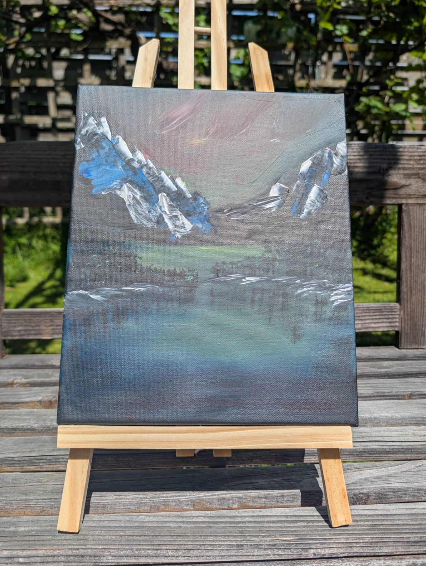 Zwischen den Bergen Berglandschaft mit See und schneebedeckten Gipfeln unter einem bewölkten Himmel.